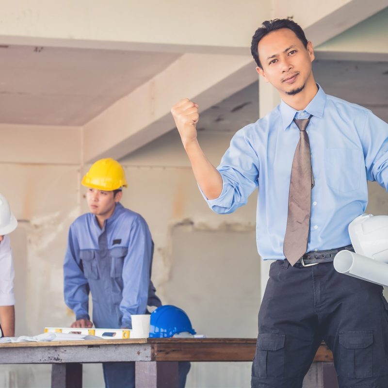 The team leader is confident in building. There is a background worker blurry.