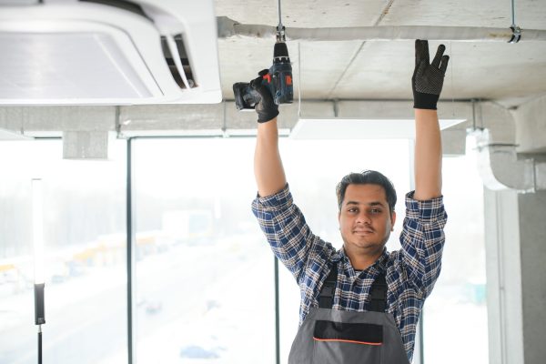 Portrait of young male technician repairing air conditioner. Air conditioner repairs.
